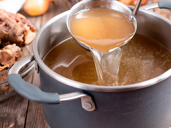 Clear golden bone broth showing rich collagen content