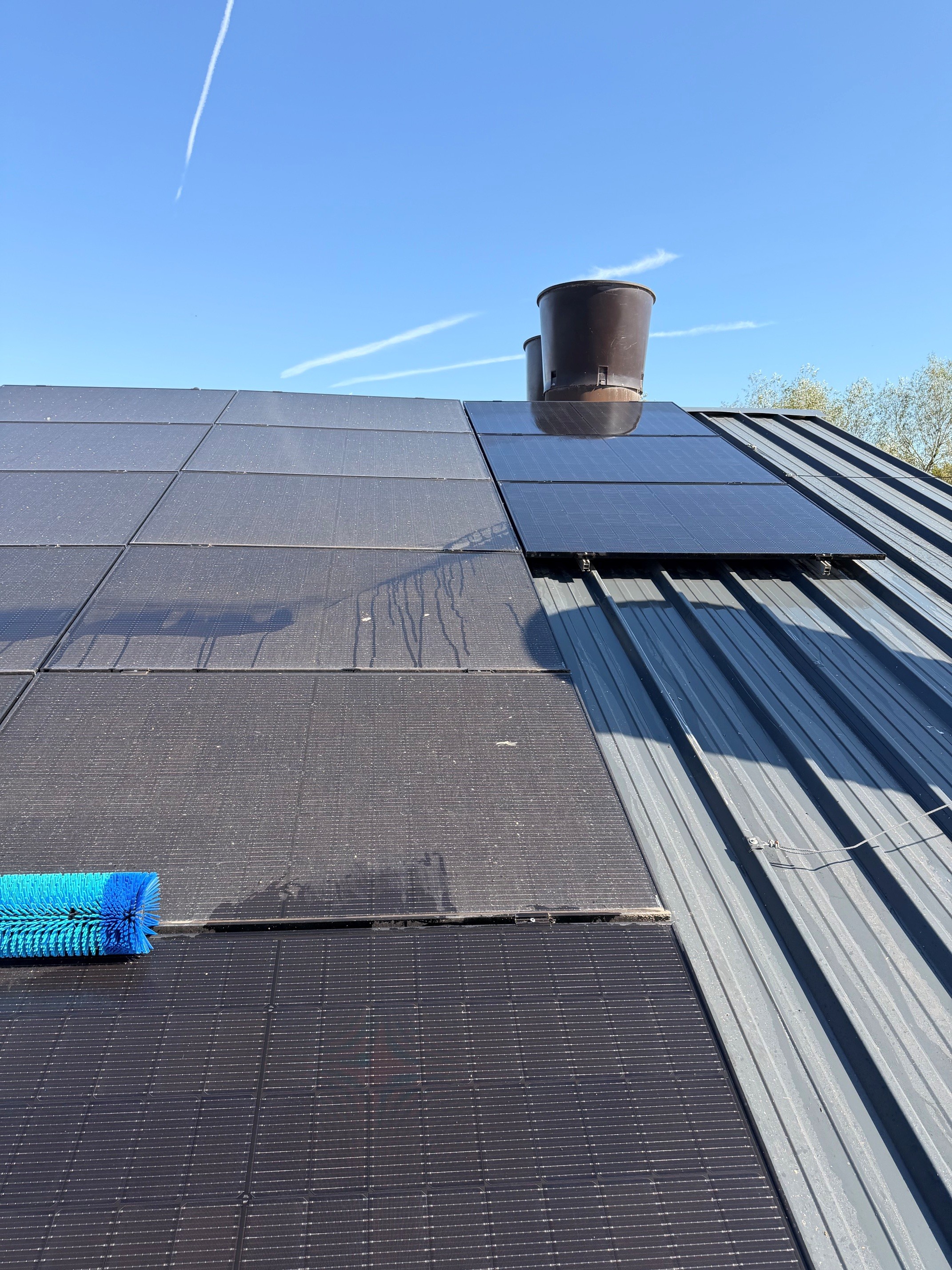 Hofdach von Bauer Jansen in Lindlar während der Reinigung: oben rechts bereits gereinigte Solarmodule, links daneben noch verschmutzte Module – direkter Vergleich auf derselben Anlage