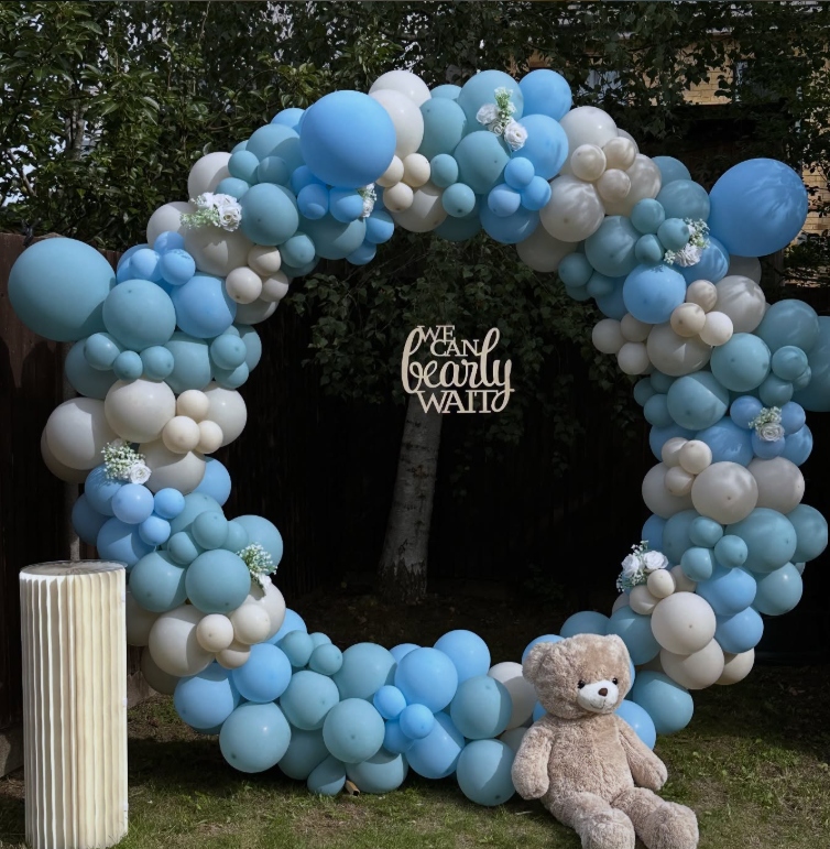 Circular organic balloon arch in blue, grey and white with a teddy bear and We Can Bearly Wait sign