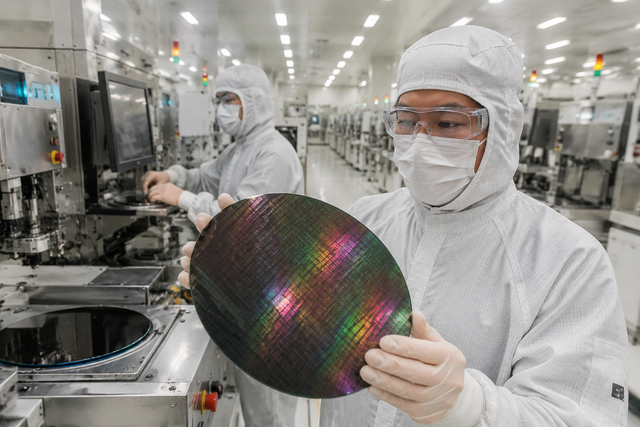 Photorealistic documentary photograph of a semiconductor fabrication clean room with technicians in white protective suits inspecting silico