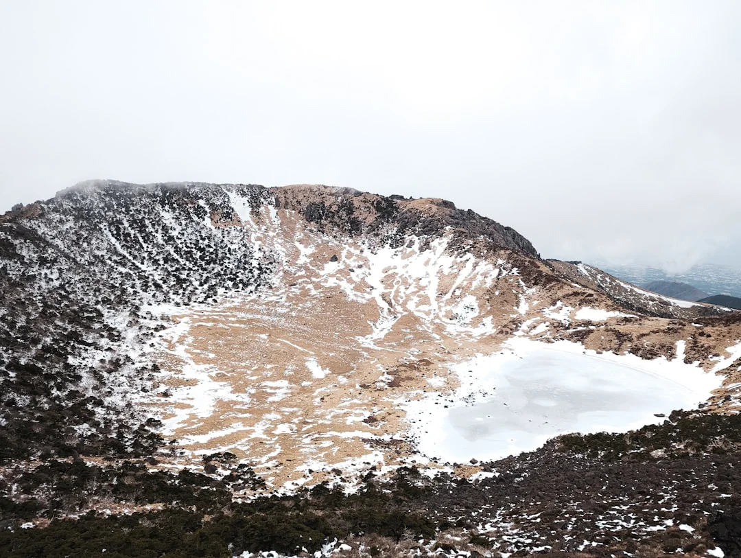 Baengnokdam crater lake at Hallasan summit in winter, volcanic rock rim and snow-covered slopes at 1,947 m peak on Jeju Island, South Korea
