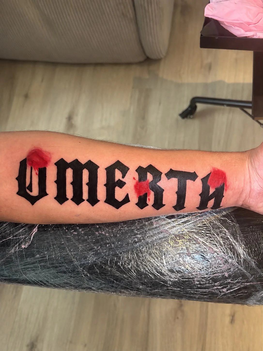 Schwarz-rotes Blackletter-Tattoo aus dem Portfolio von Flocka Tattoo