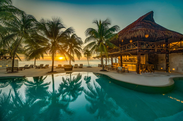 Resort con alberca y palmeras en Riviera Maya