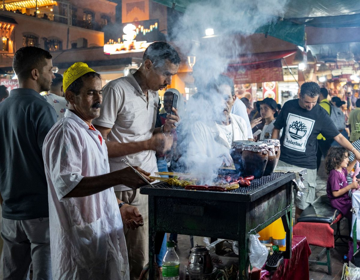 Grillades et jarres de tanjia sur un stand de street food le soir à Marrakech
