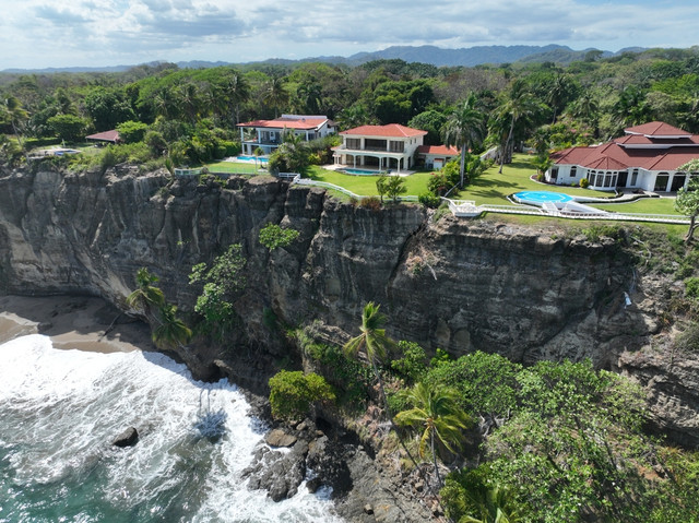 Cliffside luxury villas overlooking the ocean in Santa Teresa, Costa Rica – a prime location for beachfront property investment offering natural beauty and high rental demand.