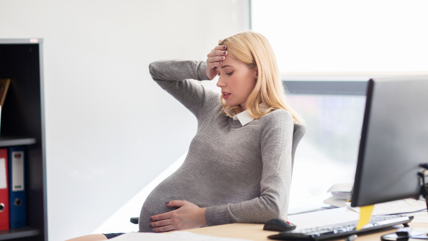 Stressed pregnant woman at work showing the problem MAIA solves