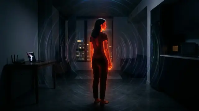Person radiating warm infrared glow surrounded by invisible electromagnetic waves in dark room