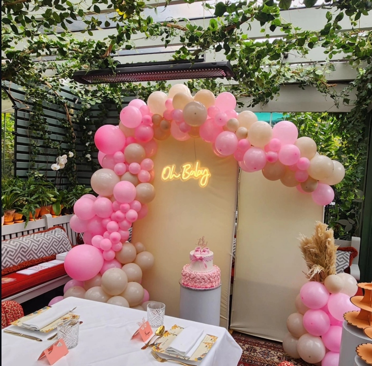 Oh Baby neon sign baby shower backdrop with pink and neutral tone balloon garland