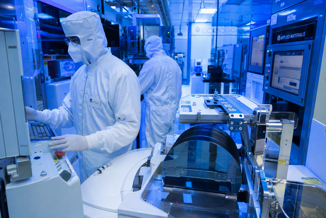Photorealistic photojournalistic image of a semiconductor fabrication cleanroom with engineers in white bunny suits overseeing wafer product